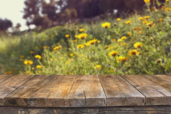 Wood board table in front of summer landscape with double exposure of flower field bloom