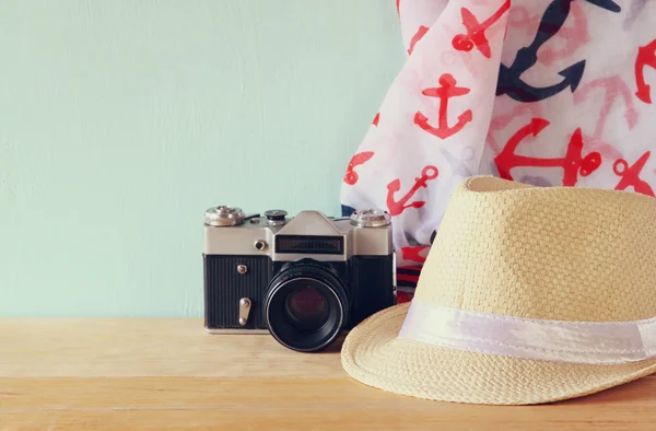Fedora hat, scarf and old vintage camera over wooden table. relaxation or vacation concept