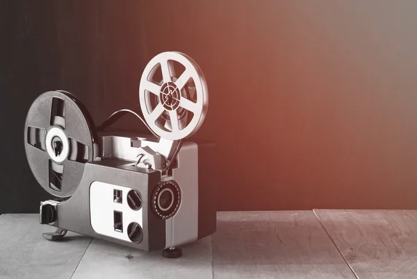 Old 8mm Film Projector over wooden table and textured background