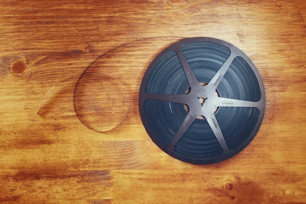 Top view image of old 8 mm movie reel over wooden background