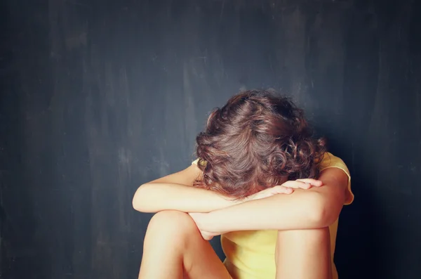 Little kid sitting and scared with his face covered between arms. kid abuse concept