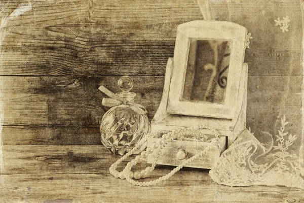 Vintage pearls , antique wooden jewelry box with mirror and perfume bottle on wooden table. black and white style photo