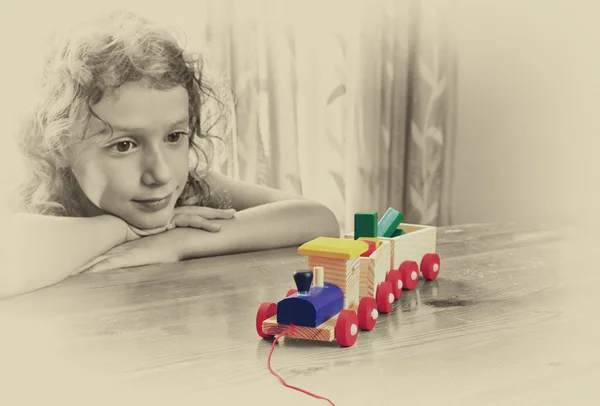 Kid looking at wooden train.