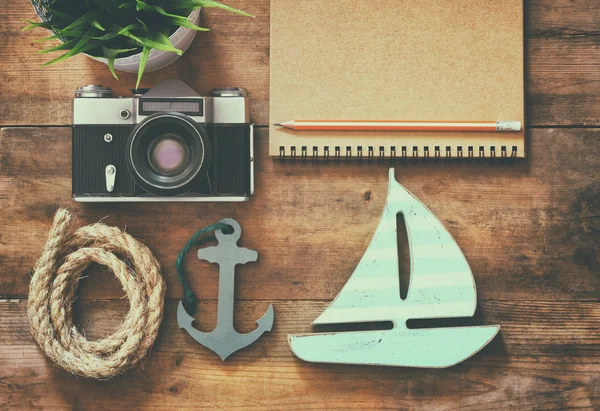 Top view image of notebook, wooden sailboat, nautical rope and camera. travel and adventure concept. retro filtered image.