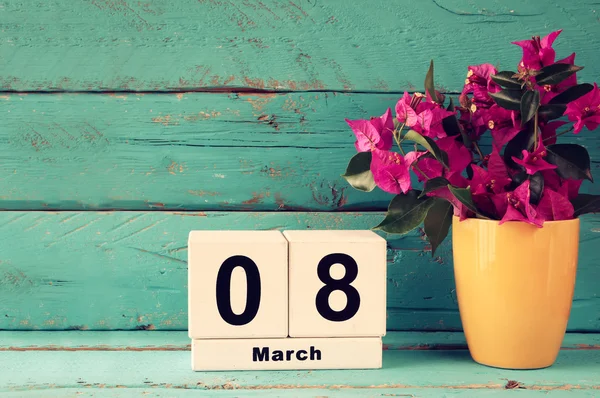 Wooden March 8 calendar, next to purple flowers on old blue rustic table. selective focus. vintage filtered