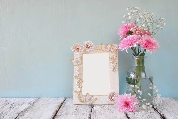 Image of pink and white flowers and antique frame on wooden table. template, ready to put photography