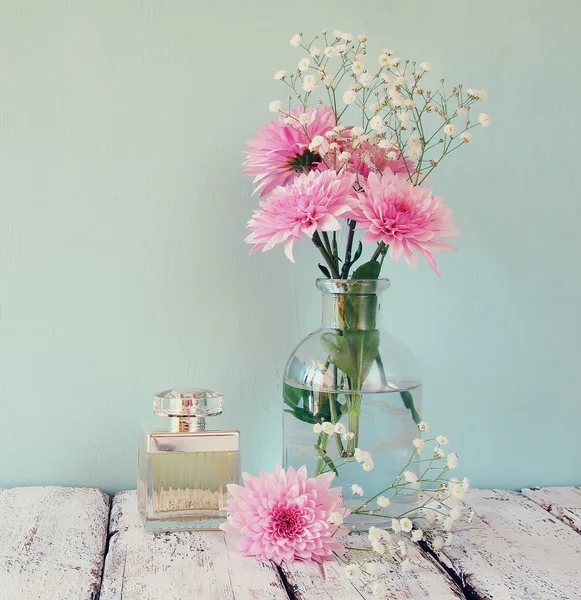 Vintage perfume bottle next to white flowers on wooden table