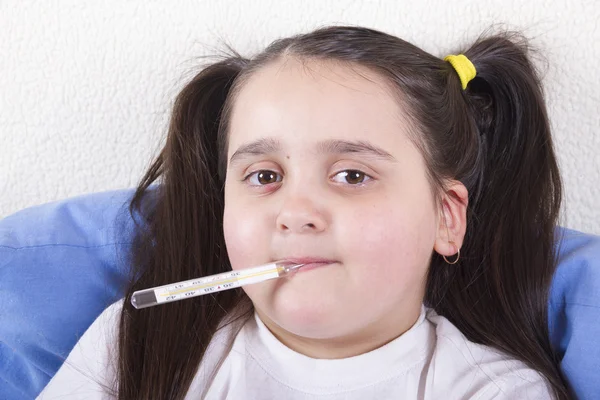 Positive sick girl with a thermometer in the mouth to measure the temperature