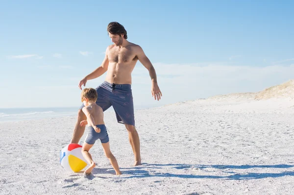 Father and son playing with ball on beach
