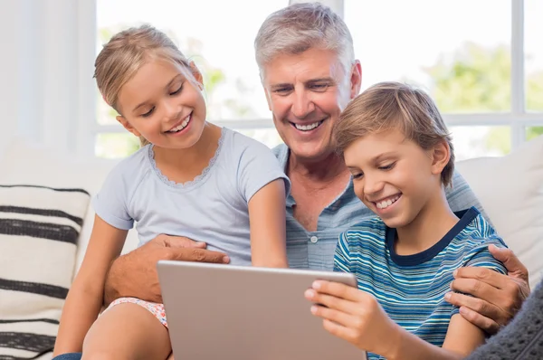 Grandchildren with grandfather using tablet