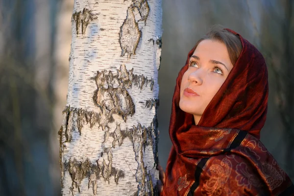 Russian girl in a scarf in a birch forest, close-up