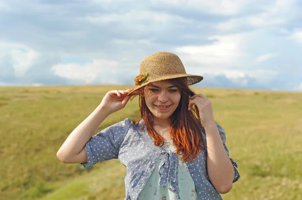 Girl in a straw hat, wind in the field