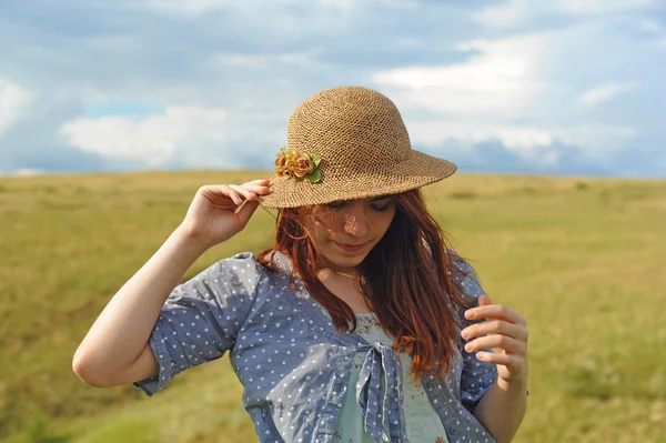Girl in a straw hat, wind in the field