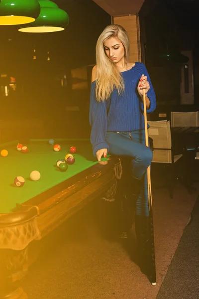 Glamour beauty woman plays billiard on pool table