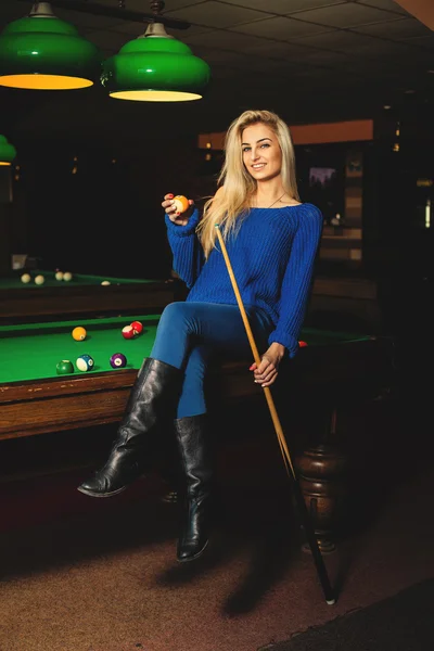 Fun sexual lady posing on pool table with the cue and ball in ha