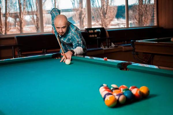 Guy concentrating on breaking pyramid of balls in the table angl