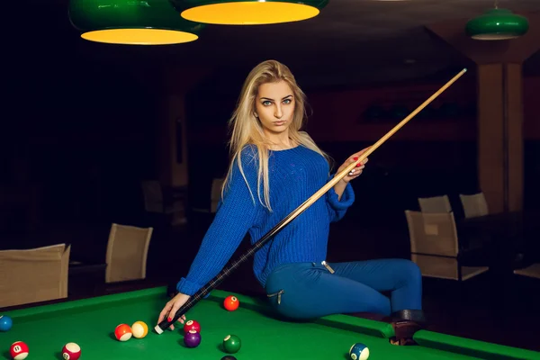 Horizontal portrait of serious blonde woman posing with the cue