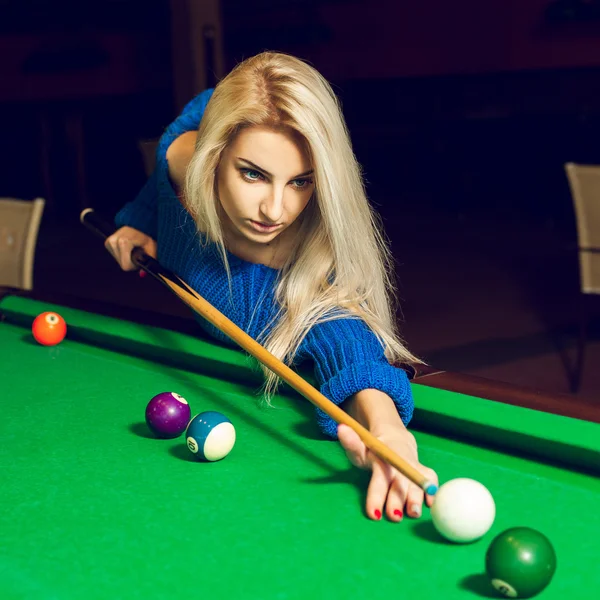 Square portrait of a serious young blond woman playing billiards