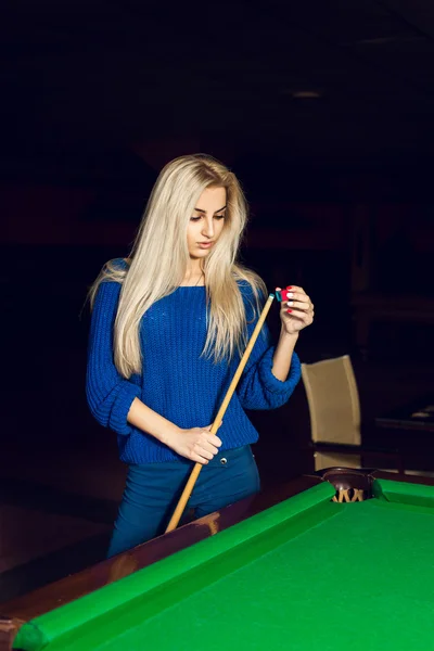 Vertical portrait of a charming blonde rubbed cue chalk
