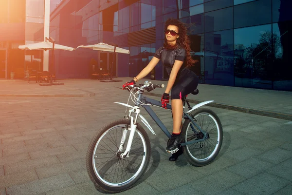 Cute brunette sports woman in sunglasses on a bicycle
