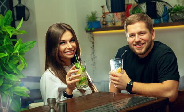 Couple drinks cocktails in the bar and smiling on camera