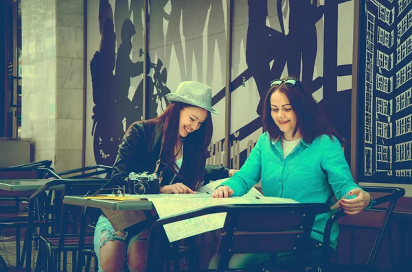 Two women sitting at a table on the street