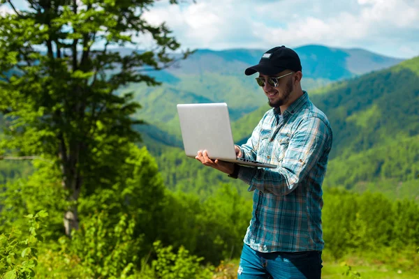 Boy smiling and working on laptop in the mountains