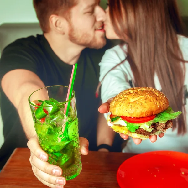 Beautiful couple kisses on background and holding a cockatil and