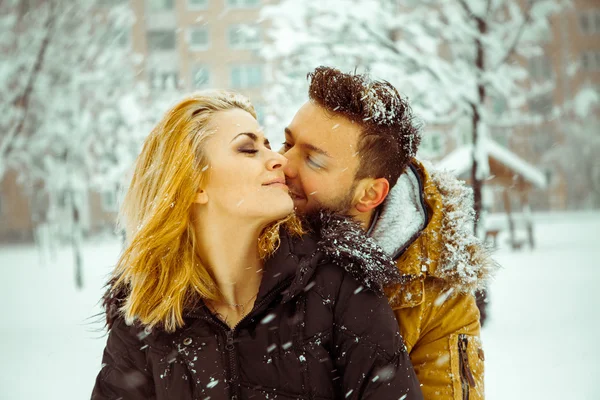Attractive couple hugging each other in the snow outdoors