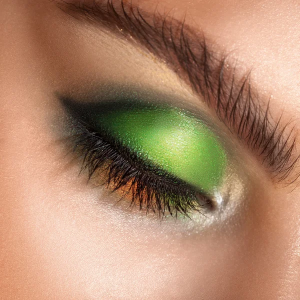 Macro photo of closed eyes with professional green colors makeup