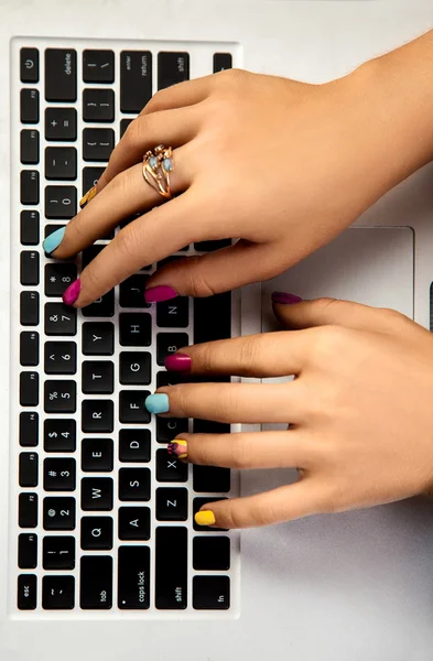 Women\'s hands with a nice manicure typing on a laptop