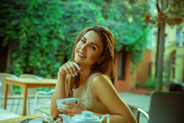 Beautiful young woman with cup of tea smiling to you