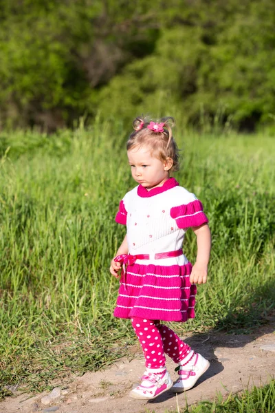 Little child girl on grass on meadow.