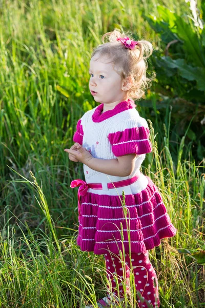 Little child girl on grass on meadow.