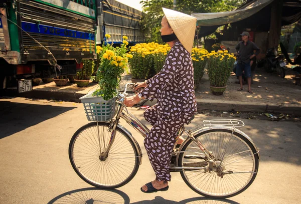 Vietnamese woman in hat drives bike
