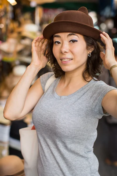 Young asian woman tries on a hat