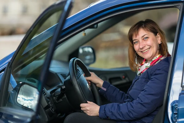 Happy young woman in new car