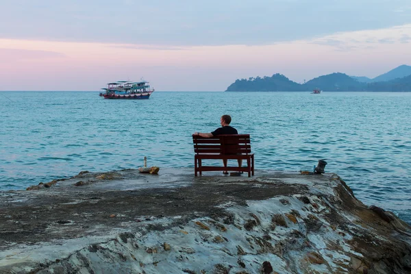 Man on bench at sea coast