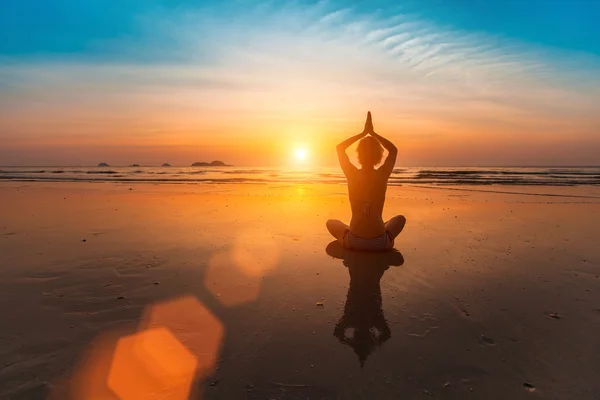 Girl sitting in yoga pose on the beach