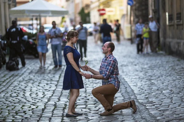Man on knees gives a woman a flower