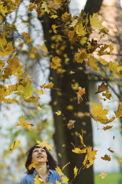 Woman looks up at the falling leaves