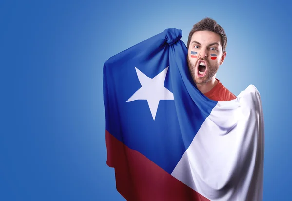 Fan holding the flag of Chile on blue background