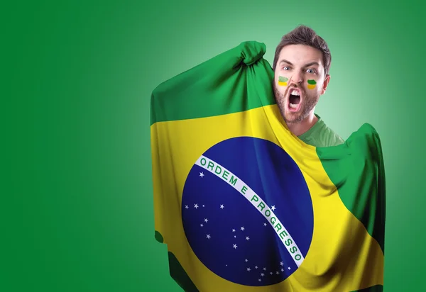 Fan holding the flag of Brazil on green background