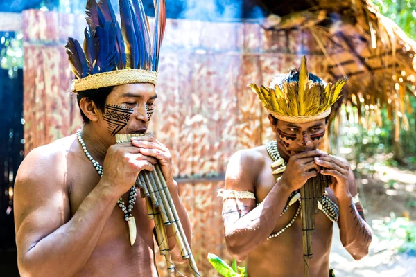 Native Brazilians playing wooden flute at an indigenous tribe in the Amazon