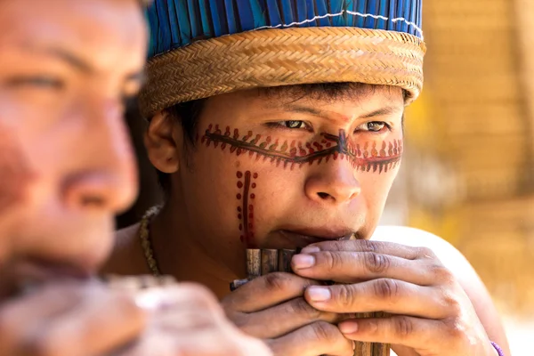 Native Brazilian guys playing wooden flute
