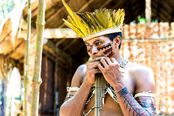 Native Brazilian playing wooden flute at an indigenous tribe in the Amazon
