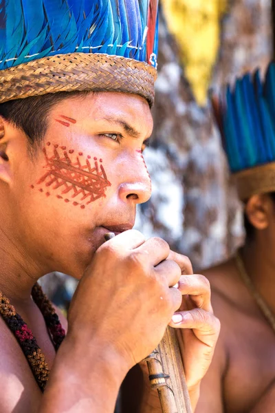 Native Brazilian guys playing wooden flute at an indigenous tribe in the Amazon