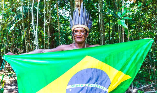 Native Brazilian man holding the Brazilian flag in the jungle in Amazon