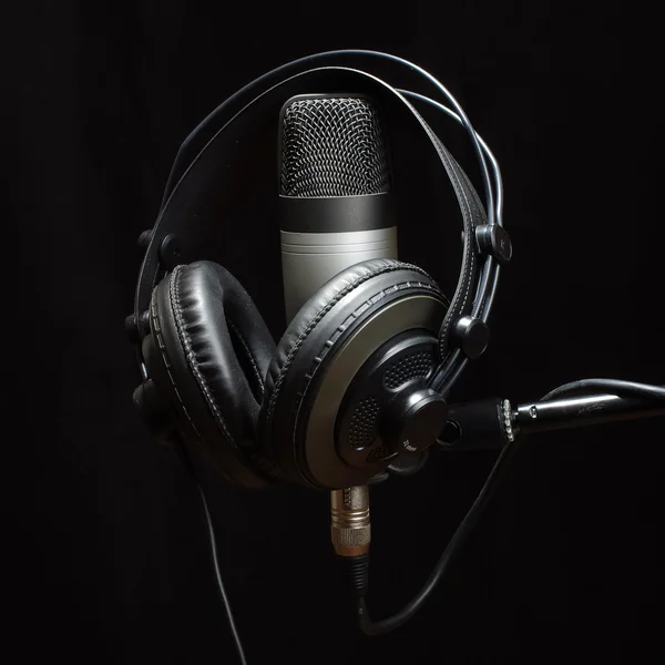 Headphones and condenser microphone isolated on the dark background