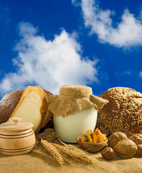 Mage of bread, nuts, wheat and dairy in the sky background closeup